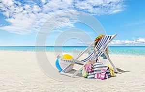 Beach deck chair for sunbathing on a sunny day by the seaside, beach ball and a bag full of accessories, concept of a summer beach