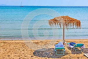 Beach with deck chairs and straw umbrella by the sea