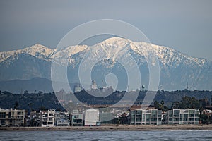 Beach and DTLA skyline with snow capped mountains