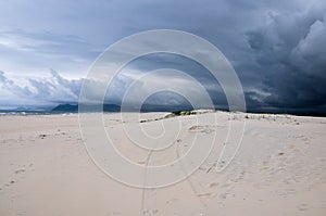 Beach dunes with whit mountains and storm coming to the background