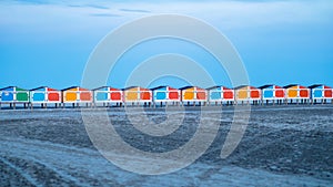 Beach at dusk with colorful row of storage containers against clear skies