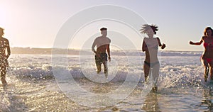 Beach, energy and friends playing in ocean together for fun on travel, vacation or holiday in summer. Splash, wave and