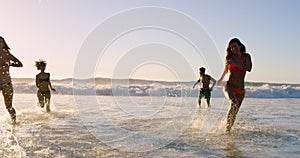 Beach, energy and splash with friends in ocean together for fun on travel, vacation or holiday in summer. Playing, wave