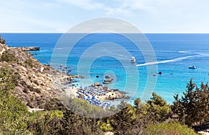 Beach equipped with sun loungers, umbrellas and rescue tower in small bay of Cyprus, on the Mediterranean coast