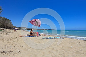 On the beach of Eraclea Minoa in Agrigento a family relaxing under an umbrella