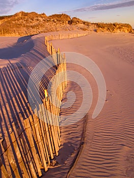 Beach fence on dunes at sunset