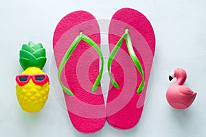 beach flip flops and squishy toy pineapple in sunglasses and flamingo on white background copy space