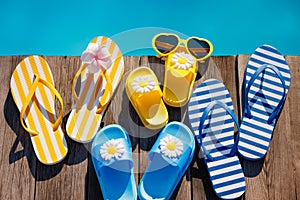 Beach flip-flops and sunglasses on wooden planks near swimming pool