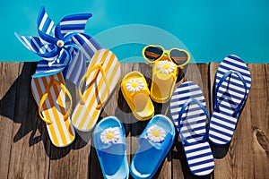 Beach flip-flops and sunglasses on wooden planks near swimming pool