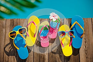 Beach flip-flops and sunglasses on wooden planks near swimming pool