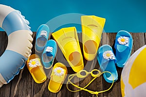 Beach flip-flops and sunglasses on wooden planks near swimming pool