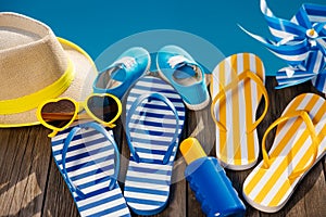 Beach flip-flops and sunglasses on wooden planks near swimming pool