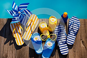 Beach flip-flops and sunglasses on wooden planks near swimming pool