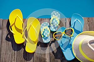 Beach flip-flops and sunglasses on wooden planks near swimming pool