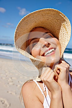 Beach fun. Portrait of a smiling young woman in a sunhat enjoying a day at the beach.