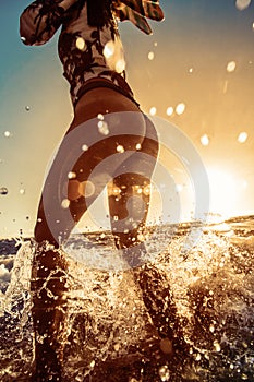 Beach girl stand in splashes in water