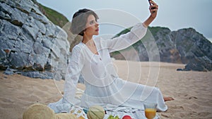 Beach girl taking selfie on cloudy weekend. Beautiful woman resting shore picnic