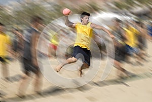 Beach handball player jumping with ball