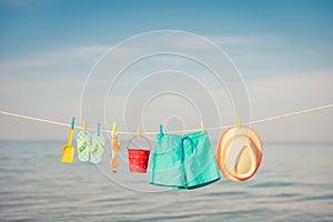 Beach hat, flip-flops and goggles hanging on a clothesline against sea and sky