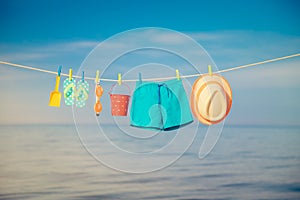 Beach hat, flip-flops and goggles hanging on a clothesline against sea and sky