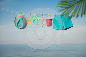 Beach hat, flip-flops and goggles hanging on a clothesline against sea and sky