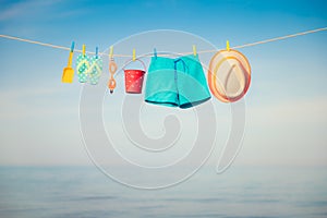 Beach hat, flip-flops and goggles hanging on a clothesline against sea and sky