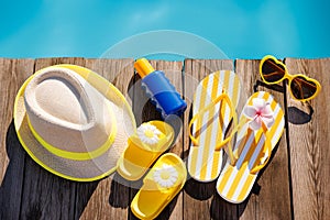 Beach hat, flip-flops and sunglasses on wooden planks near swimming pool