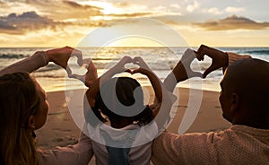 Beach, heart hands and family for love of summer, ocean and outdoor wellness with parents, child and sunset sky clouds