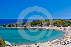 Beach with holiday-makers, sun beds and umbrellas in village