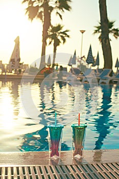 Beach holidays background with two cocktails In mermaid tail glass near swimming pool in luxurious hotel