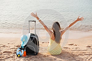 Beach holidays woman enjoying summer sun sitting in sand looking happy at copy space. Beautiful young model