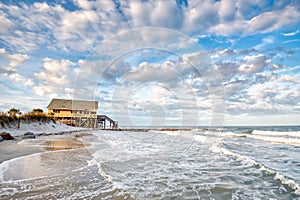 A beach house on stilts over the beach.