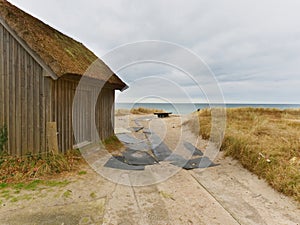 Beach hut at sand dunes, end of road next sea. Old wooden house for fishers.