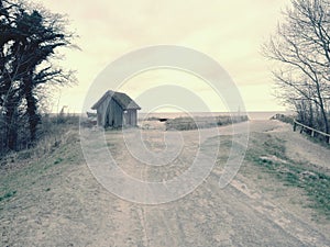 Beach hut at sand dunes, end of road next sea. Old wooden house for fishers.