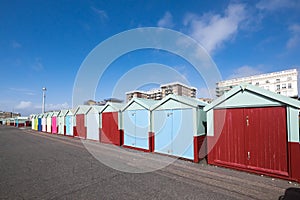 Beach huts on Hove seafront in Brighton, Sussex, UK, with apartment block buildings with blue sky