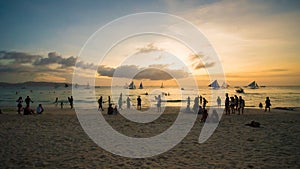 Beach on the island of Boracay in the rays of the evening sunset. Silhouettes of people playing a ball on the beach and