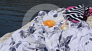 Beach items - swimwear, sun protection cream and a shell on a seashore rock