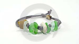 Beach jewelry - bracelet made of beach pebbles, sea glass and green cord on white background. Handmade gift concept
