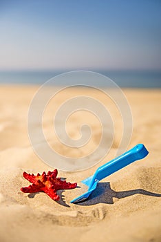 Beach with kid toys shovel, bucket and red sea star
