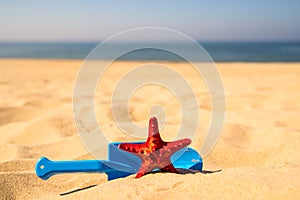 Beach with kid toys shovel, bucket and red sea star