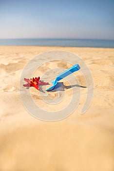 Beach with kid toys shovel, bucket and red sea star