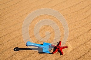 Beach with kid toys shovel, bucket and red sea star