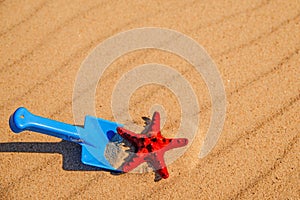 Beach with kid toys shovel, bucket and red sea star