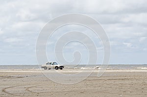 Beach landscape, a car standing in the sand with the sea in the background