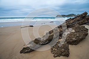 Beach landscape with rock in the foreground, a cloudy afternoon, with bluish tones, in Comillas, Cantabria, photo