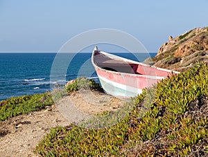 Beach landscape - Skiff boat on the cliff photo