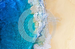 Beach and large ocean waves. Coast as a background from top view. Blue water background from drone. Summer seascape from air.