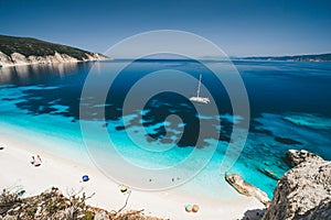 Beach leisure activity. Fteri bay, Kefalonia, Greece. White catamaran yacht in clear blue sea water. Tourists on sandy photo