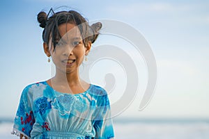 Beach lifestyle portrait of young beautiful and happy Asian child girl 8 or 9 years old with cute double buns hair style playing