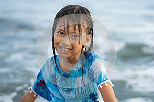 Beach lifestyle portrait of young beautiful and happy 7 or 8 years old Asian American mixed child girl with wet hair enjoying